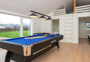 Salle de jeux dans maison de vacances à Sydals, Danemark, avec billard bleu et baies vitrées.