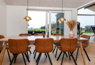 Salle à manger avec huit chaises en cuir, grande table et vues extérieures dans une maison de vacances à Sydals.