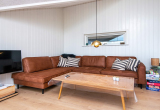 Woonkamer in vakantiehuis in Sydals, Denemarken, met bruine sofa, salontafel en gezelschapsspellen.
