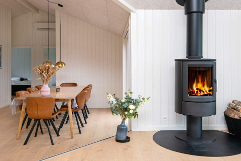 Moderne eetruimte met houtkachel, lederen stoelen en bloemen in een vakantiehuis in Sydals, Denemarken.