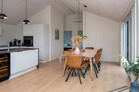 Moderne eet- en keukenhoek met bruine leren stoelen en houten tafel in een vakantiewoning te Sydals, Denemarken.