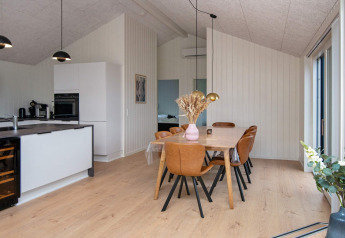 Moderne eet- en keukenhoek met bruine leren stoelen en houten tafel in een vakantiewoning te Sydals, Denemarken.