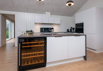 Moderne Küche in einer Ferienwohnung in Sydals, Dänemark, mit Weinkühlschrank und hellen Möbeln.