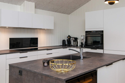 Moderne køkken i feriebolig med hvidt interiør, ø, integrerede apparater og elegant belysning i Sydals, Danmark.