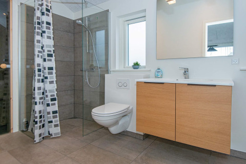 Bagno moderno in casa vacanze per 8 persone a Sydals, Danimarca, con doccia in vetro e mobile in legno.