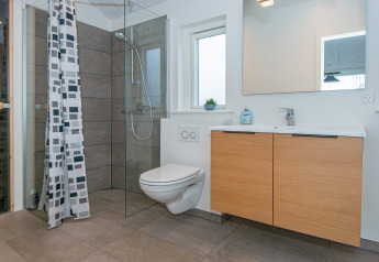 Bagno moderno in casa vacanze per 8 persone a Sydals, Danimarca, con doccia in vetro e mobile in legno.
