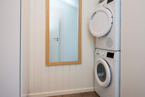 Wasruimte in vakantiehuis in Sydals, Denemarken, met gestapelde wasmachine en droogkast naast een spiegel.