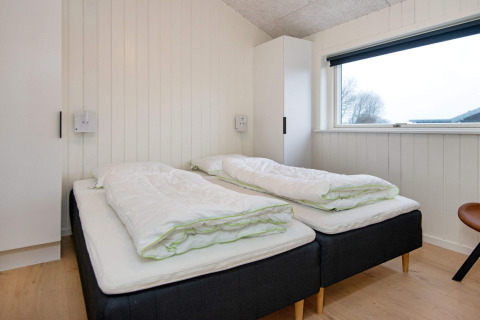 Chambre avec deux lits simples, couettes blanches et grande fenêtre dans maison de vacances 8 personnes à Sydals, Danemark.