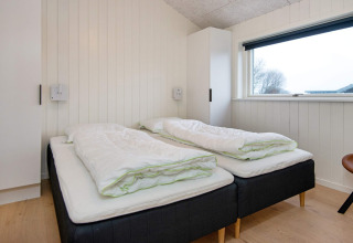Chambre avec deux lits simples, couettes blanches et grande fenêtre dans maison de vacances 8 personnes à Sydals, Danemark.