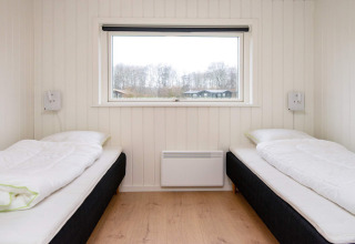 Zwei Einzelbetten in einem hellen Zimmer mit Holzverkleidung und großem Fensterblick in Sydals, Dänemark.