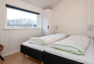 Bedroom with two single beds, large window, and wardrobe in holiday home in Sydals, Denmark.