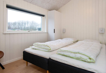 Slaapkamer met twee enkele bedden, groot raam en kast in vakantiehuis in Sydals, Denemarken.