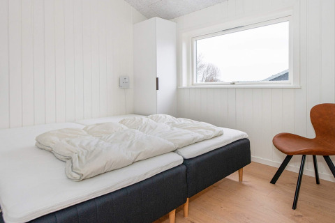 Lichte slaapkamer in een vakantiewoning in Sydals, Denemarken, met twee bedden, stoel en raam.
