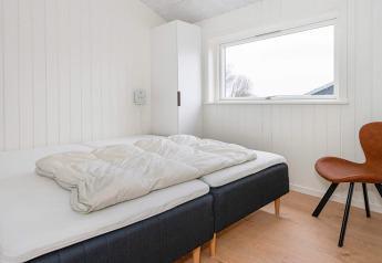 Chambre lumineuse dans une maison de vacances à Sydals, Danemark, avec deux lits simples et une chaise.
