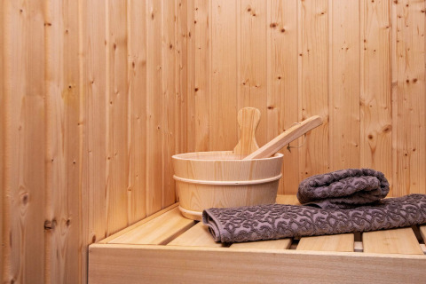 Houten sauna met emmer en grijze handdoeken op bank in ‘8-persoons vakantiehuis in Sydals’, Denemarken.