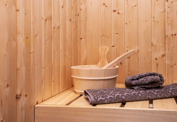Houten sauna met emmer en grijze handdoeken op bank in ‘8-persoons vakantiehuis in Sydals’, Denemarken.