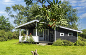 Zwart vakantiehuis met veranda in groene tuin, 6-persoons vakantiehuis in Glesborg, Denemarken.