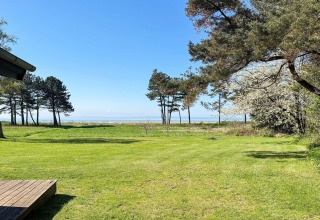 Vue depuis une maison de vacances pour 4 personnes à Knebel, Danemark, sur pelouse, arbres et mer au loin