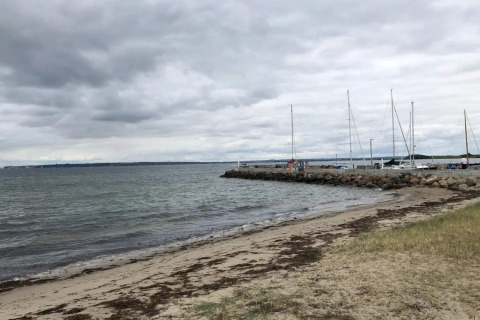 Strand, stenen en zeilboten aan de pier bij het 4-persoons vakantiehuis in Knebel, Denemarken.