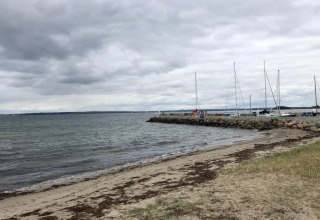 Strand, stenen en zeilboten aan de pier bij het 4-persoons vakantiehuis in Knebel, Denemarken.