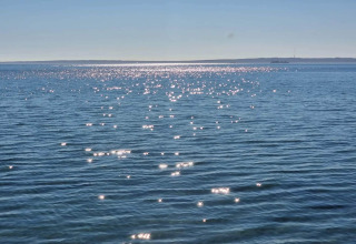 Zonneschitteringen op zee, bekeken vanaf een huisje in Knebel, Denemarken, met de horizon in zicht.