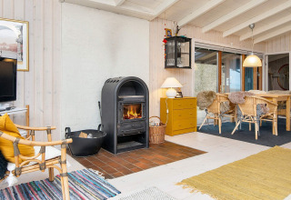 Gemütliches Wohnzimmer im Ferienhaus in Knebel, Dänemark, mit Holzofen und rustikaler Einrichtung.