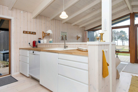 Cucina moderna e luminosa in casa vacanze per 4 persone a Knebel, Danimarca, con pannelli in legno chiaro.