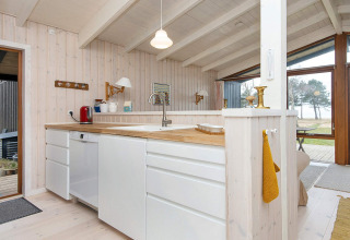 Helle, moderne Küche in einem Ferienhaus für 4 Personen in Knebel, Dänemark, mit Naturholz und Weiß.