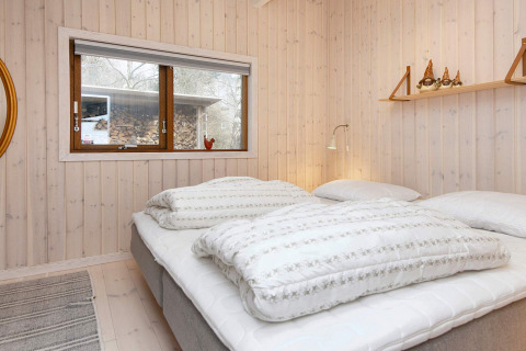Chambre dans une maison de vacances pour 4 personnes à Knebel, Danemark, lit double et murs en bois.