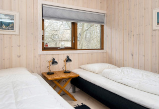 Slaapkamer in een vakantiehuis in Knebel, Denemarken, met twee eenpersoonsbedden en houten wanden.