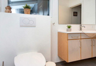 Bagno moderno con toilette e lavabo in casa vacanze per quattro persone a Knebel, Danimarca.