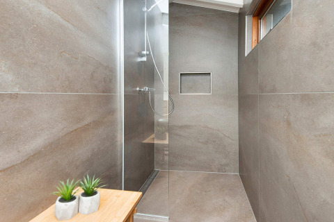 Moderne douche met grijze tegels en glazen wand in een vakantiehuis voor 4 personen in Knebel, Denemarken.
