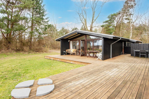 Vakantiehuisje met grote houten terras, buitenzitjes en bosrijke ligging in Knebel, Denemarken.