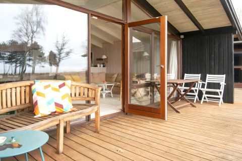 Terrazza in legno con porta aperta e sedute all’aperto presso casa vacanze per 4 persone a Knebel, Danimarca.