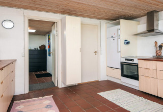 Cuisine d'une maison de vacances à Ebeltoft, Danemark, avec sol carrelé, plafond bois et équipements modernes.
