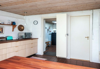 Moderne keuken in een vakantiehuis in Ebeltoft, Denemarken, met houten plafond en microgolfoven.