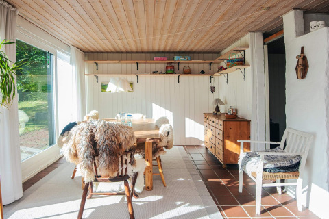 Salle à manger lumineuse dans une maison de vacances à Ebeltoft, Danemark, avec meubles en bois et vue sur le jardin.