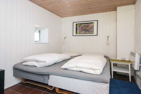 Chambre avec lit double, murs blancs, plafond en bois et œuvre colorée dans une maison à Ebeltoft, Danemark.