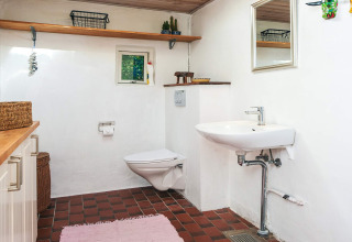 Salle de bain avec toilettes murales, lavabo et carrelage rouge dans une maison de vacances à Ebeltoft.
