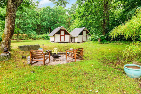 Sfeervolle vuurplaats met houten banken en hutten in de tuin van een vakantiehuis in Ebeltoft, Denemarken.