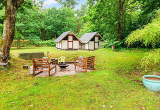 Knusse vuurplaats met houten banken en huisjes in de tuin van een vakantiehuis in Ebeltoft, Denemarken.