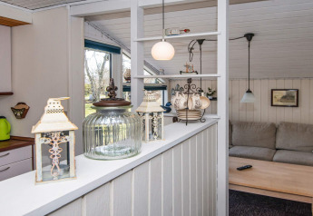 Sala y cocina de una casa de vacaciones en Glesborg, Dinamarca, con linternas decorativas y sofá beige.