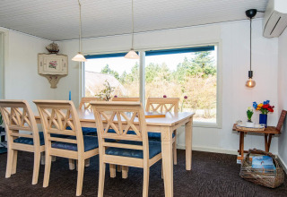 Dining area with large table, six chairs and scenic window view at 6 person holiday home in Glesborg, Denmark.