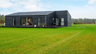 Modern 8-persoons vakantiehuis in Ansager met donkere gevel, grote ramen en uitgestrekt grasveld.