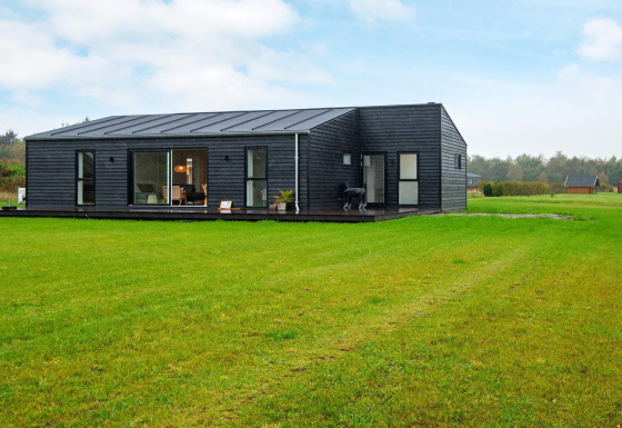 Modern 8-persoons vakantiehuis in Ansager met donkere gevel, grote ramen en uitgestrekt grasveld.
