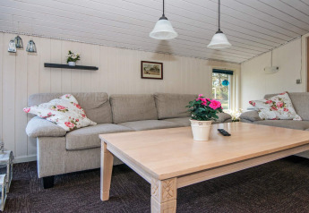 Acogedora sala de estar con sofás grises, almohadones florales y mesa decorada en Glesborg, Dinamarca.