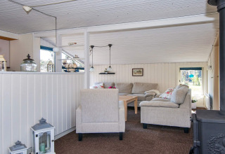 Cozy living room with beige sofas and wood stove in 6 person holiday home in Glesborg, Denmark.