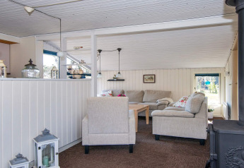 Sala acogedora con sofás beige y estufa de leña en casa de vacaciones para 6 personas en Glesborg, Dinamarca.
