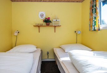 Camas individuales en un acogedor dormitorio amarillo con decoración de pared en Glesborg, Dinamarca.