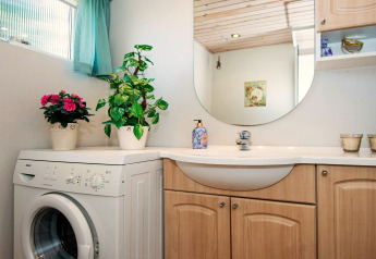 Salle de bain lumineuse dans une maison de vacances à Glesborg, Danemark, avec lave-linge et plantes.